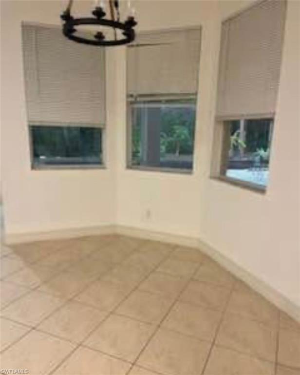 Spare room with a chandelier and light tile patterned floors