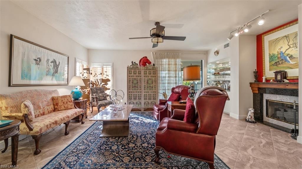 Living room featuring a high end fireplace and ceiling fan