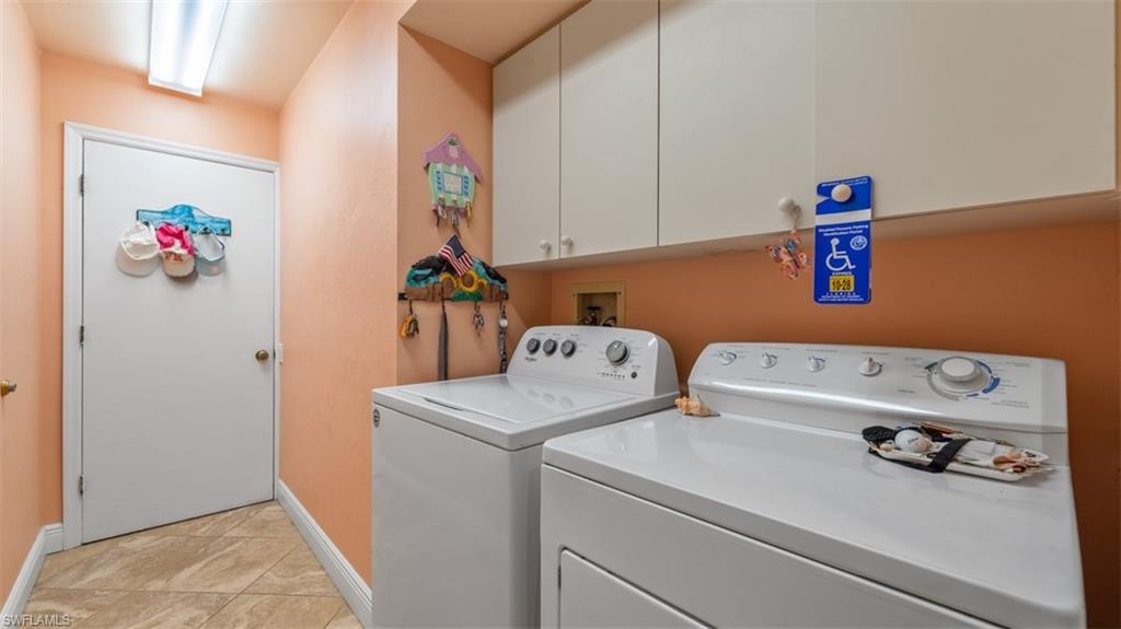 Laundry room featuring cabinet space, washing machine and dryer, and light tile patterned flooring