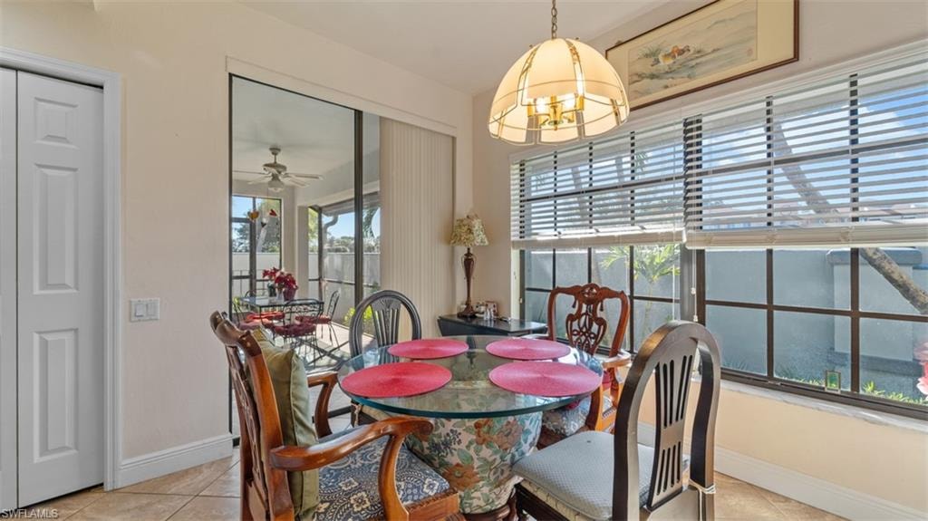 Dining space with light tile patterned flooring, ceiling fan, and a chandelier
