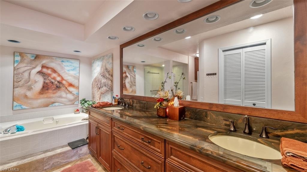 Bathroom with a shower stall, a bath, double vanity, and recessed lighting