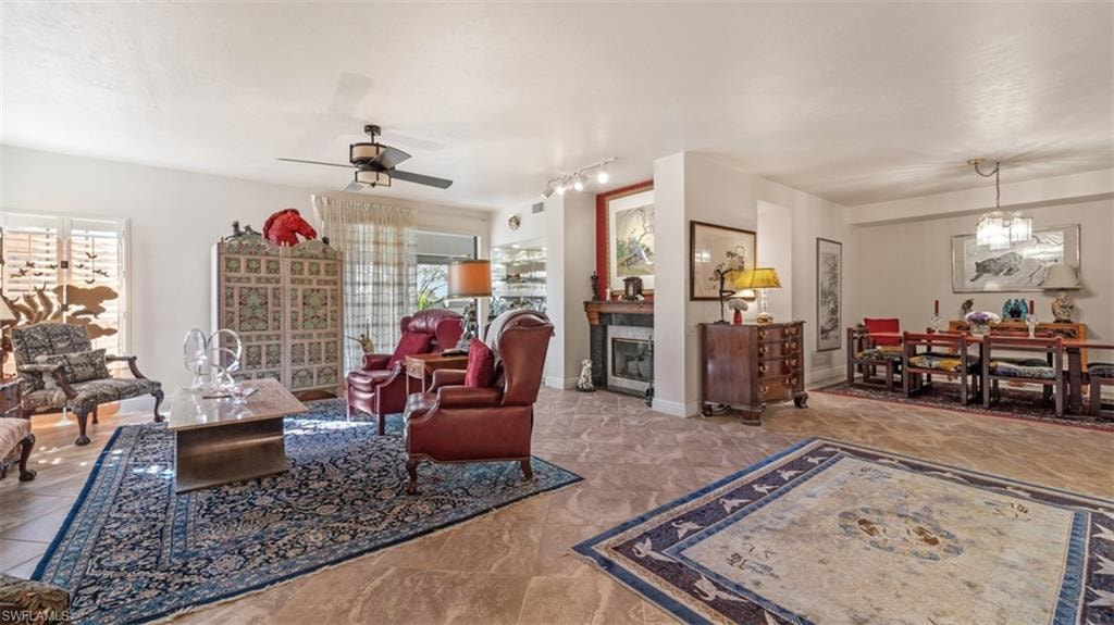 Living room featuring a fireplace, a chandelier, ceiling fan, and rail lighting