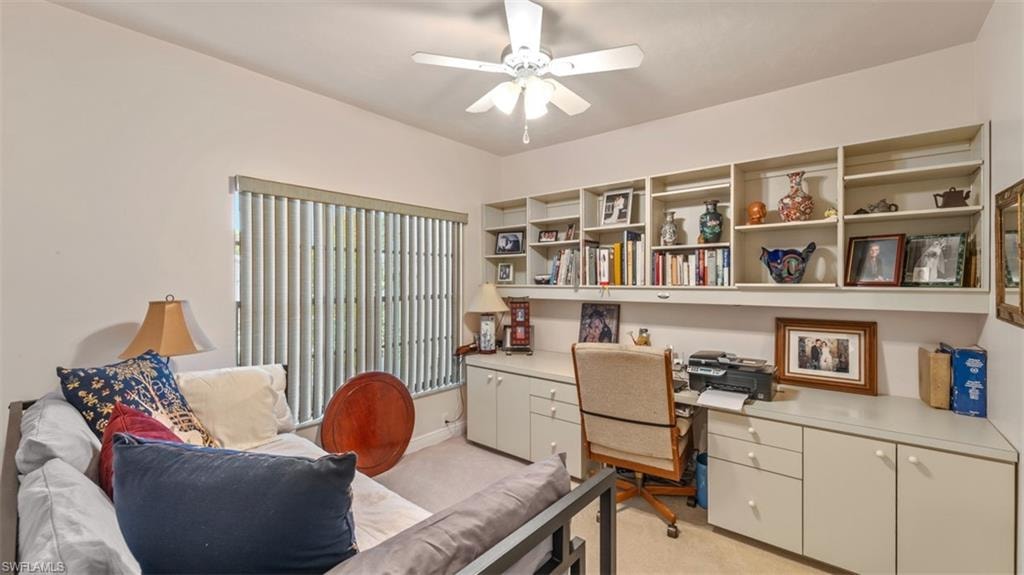 Office area featuring built in study area, light carpet, and ceiling fan