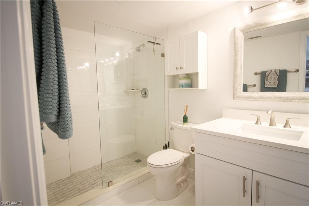 Bathroom with vanity, tiled shower, and light tile patterned floors