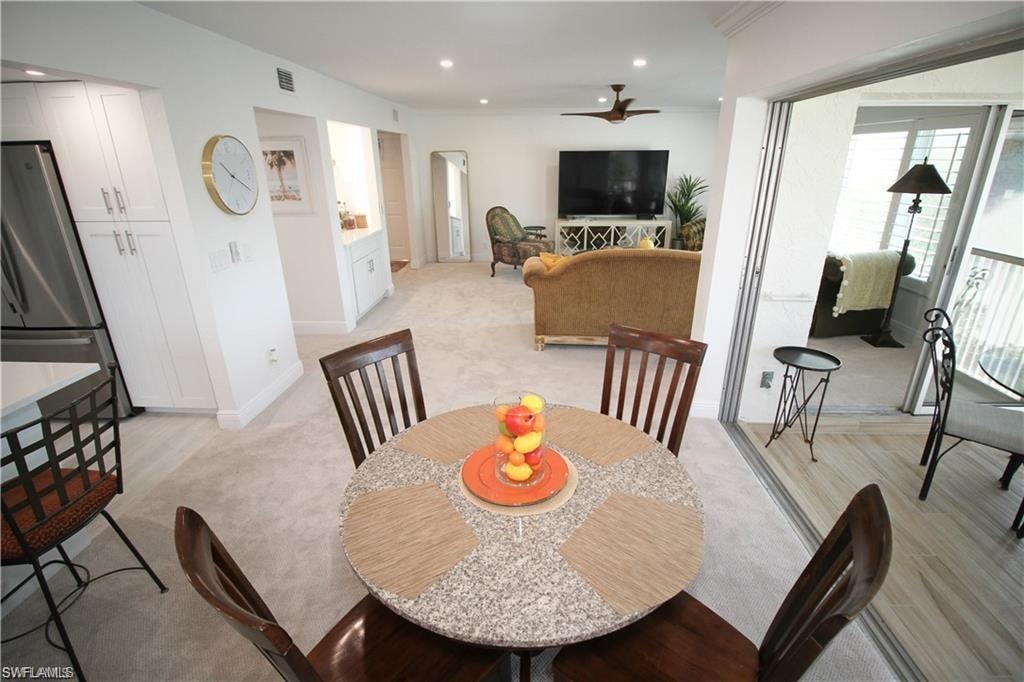 Dining space featuring arched walkways, light carpet, ceiling fan, and recessed lighting