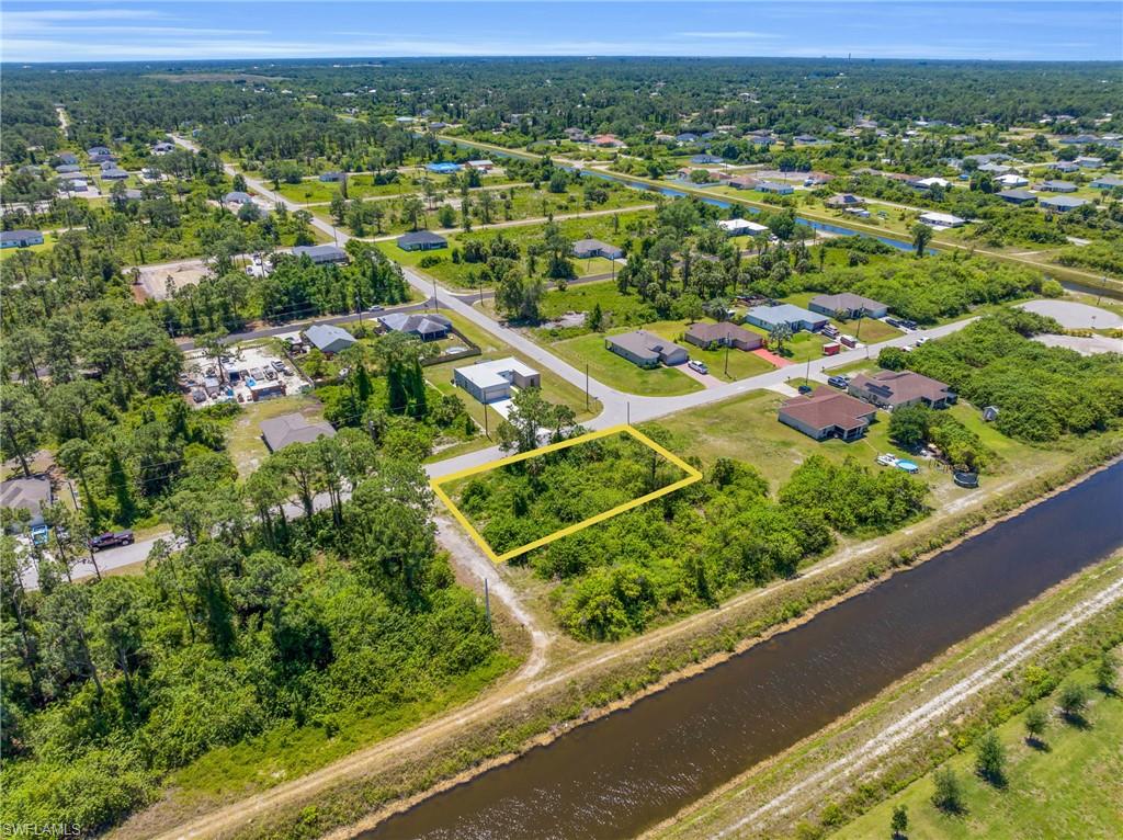 Aerial view of property and surrounding area featuring property parcel outlined, nearby suburban area, and a large body of water