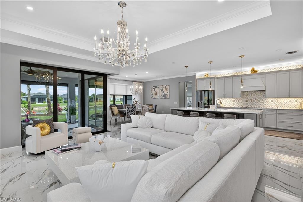 Living room with marble tiled flooring, ornamental molding, a chandelier, and recessed lighting