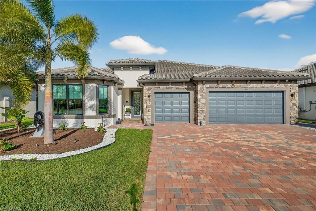 View of front of property with stone siding, decorative driveway, a front lawn, a tiled roof, and an attached garage
