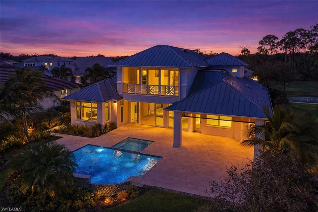 Back of property featuring a balcony, a patio area, and a standing seam roof