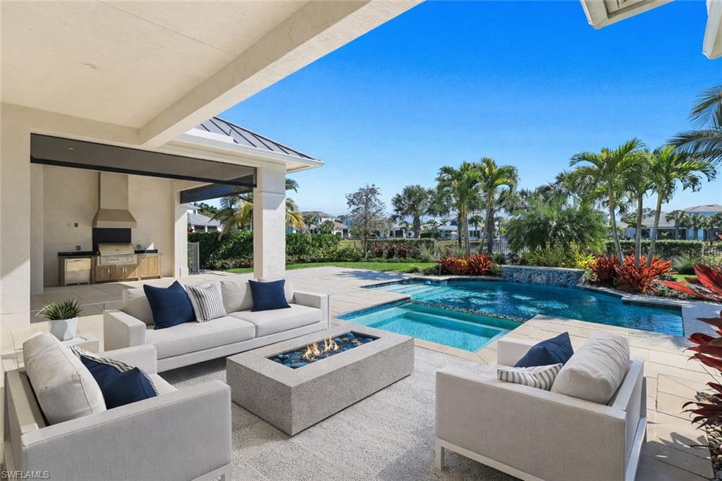 Combined pool / hot tub with an outdoor kitchen with living area, a patio area, and an outdoor fire pit