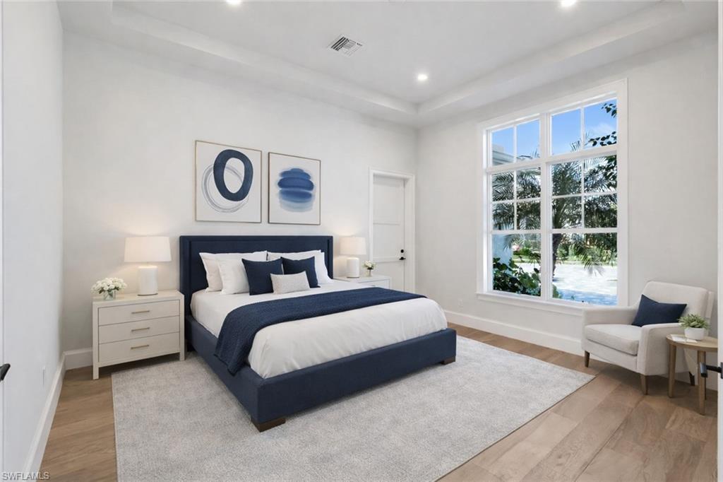 Bedroom with a tray ceiling, light wood-type flooring, and recessed lighting