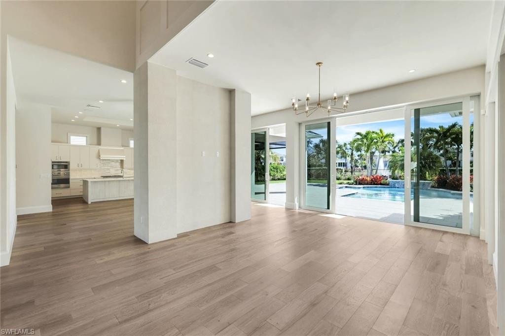 Unfurnished living room with a chandelier and light wood-type flooring