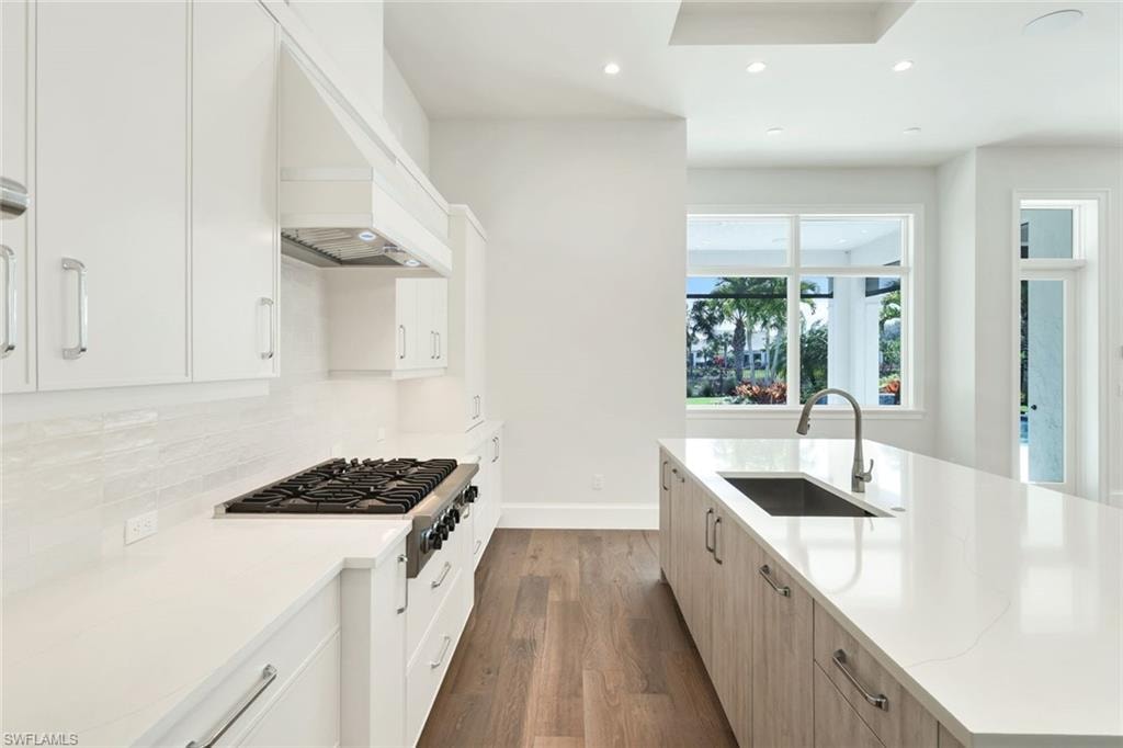 Kitchen featuring dual tone cabinets, recessed lighting, dark wood finished floors, light stone countertops, and stainless steel gas cooktop