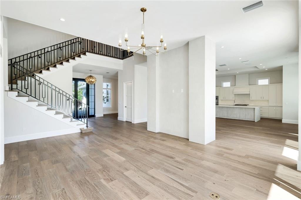 Unfurnished living room with suspended lighting and light wood-type flooring