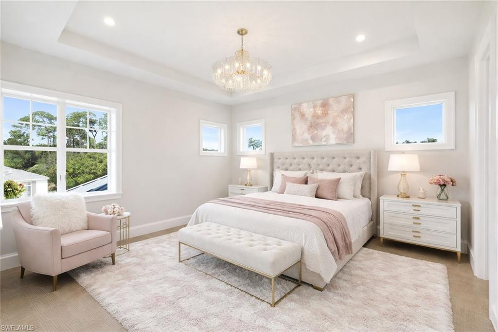 Bedroom with multiple windows, a chandelier, and a tray ceiling