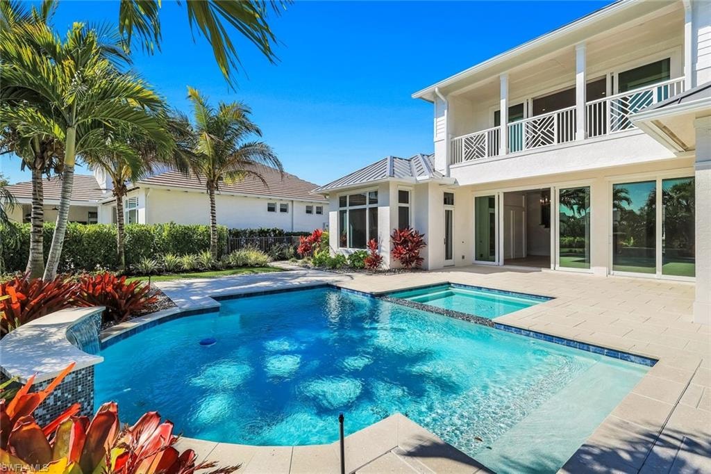 Relaxing pool / spa with a balcony and a patio