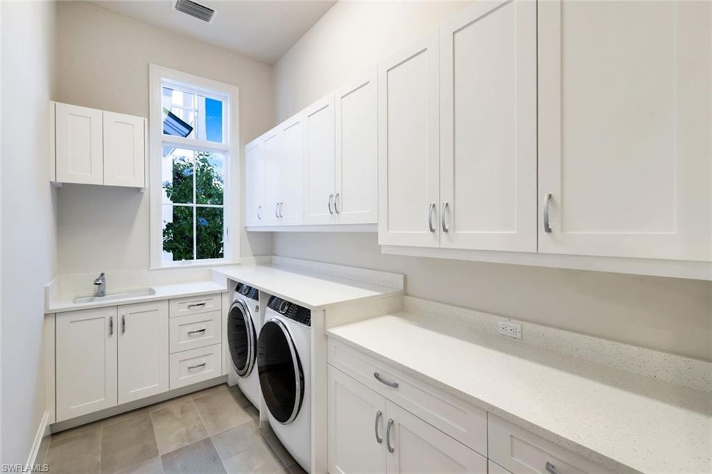 Laundry area with cabinet space, independent washer and dryer, and light tile patterned flooring