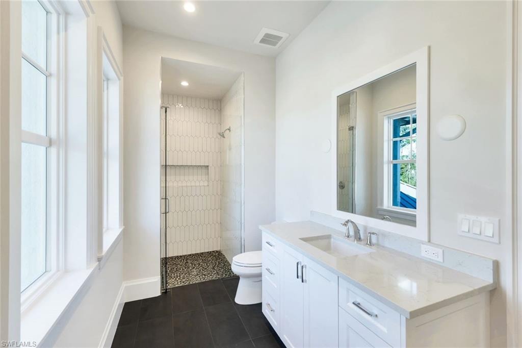 Bathroom with a shower stall, vanity, dark tile patterned flooring, and recessed lighting