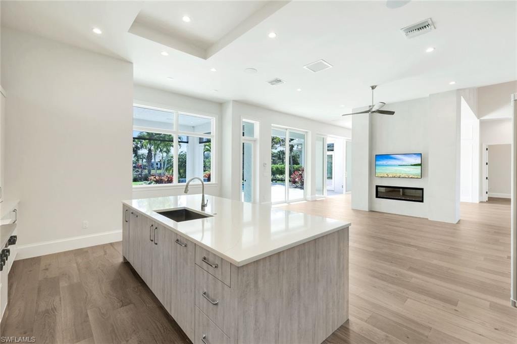 Kitchen featuring modern cabinets, light wood-type flooring, light wood finish cabinets, an island with sink, and recessed lighting