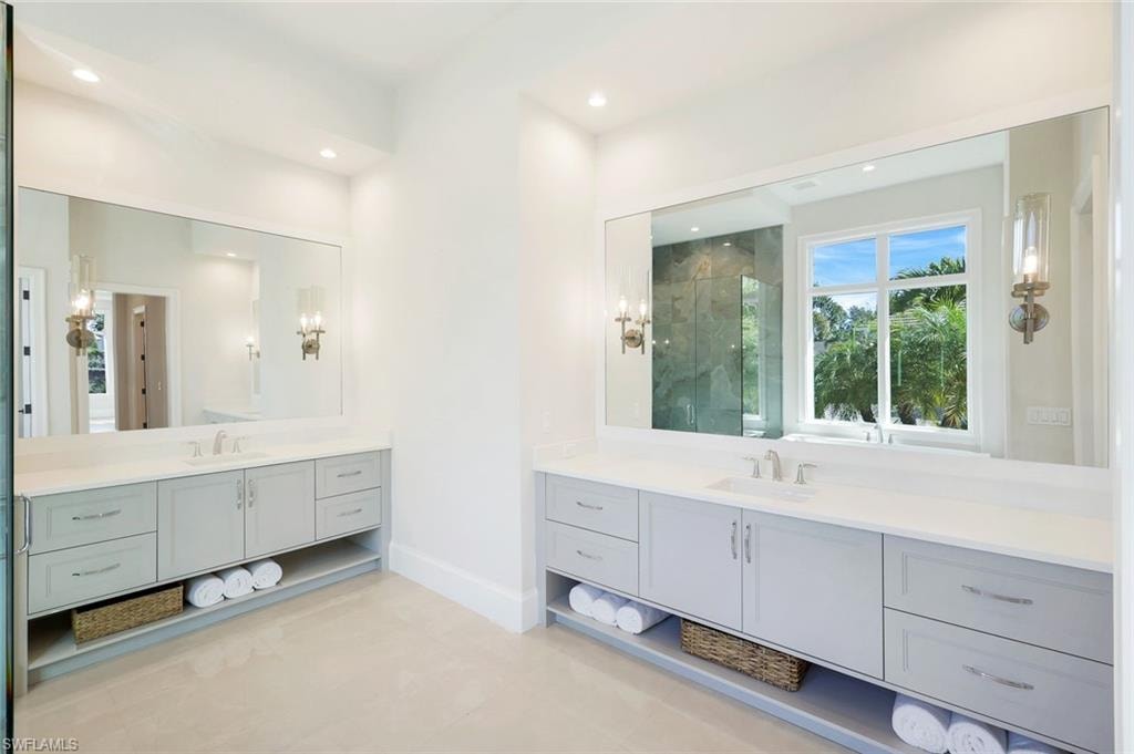 Full bathroom featuring a marble finish shower, two vanities, and recessed lighting