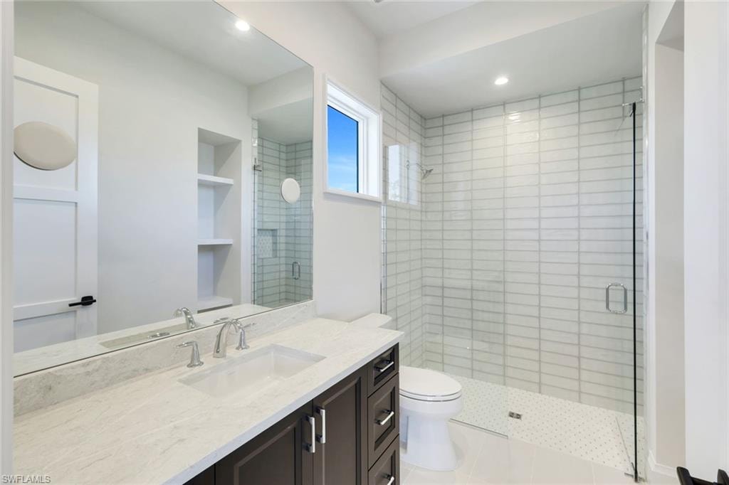 Bathroom featuring a shower stall, vanity, built in shelves, and recessed lighting