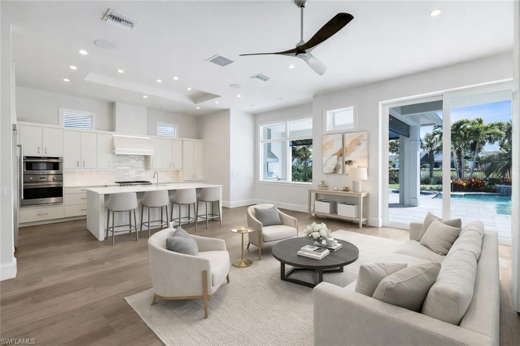 Living room featuring ceiling fan, light wood-type flooring, healthy amount of natural light, recessed lighting, and a raised ceiling