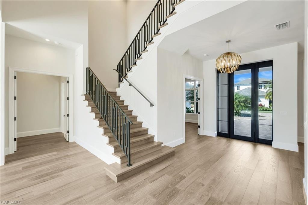 Entrance foyer featuring light wood finished floors, hanging lights, and a high ceiling