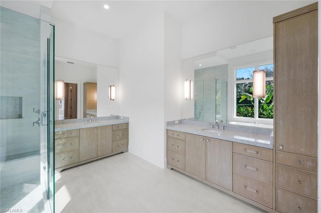 Bathroom with two vanities, a stall shower, and recessed lighting