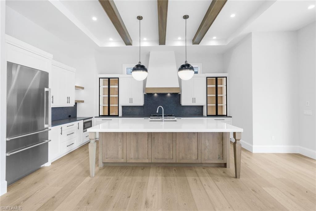 Two tone kitchen with stainless steel appliances, open shelves, tasteful backsplash, pendant lighting, and a kitchen island with sink