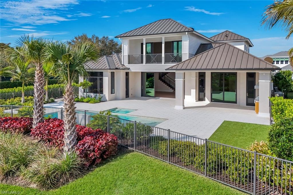 Rear view of property with a standing seam roof, a patio, a balcony, and a fenced backyard