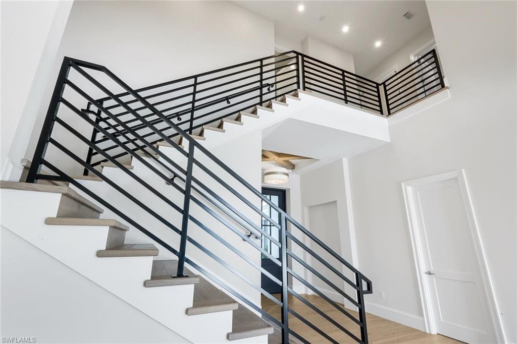 Staircase featuring wood finished floors and a high ceiling