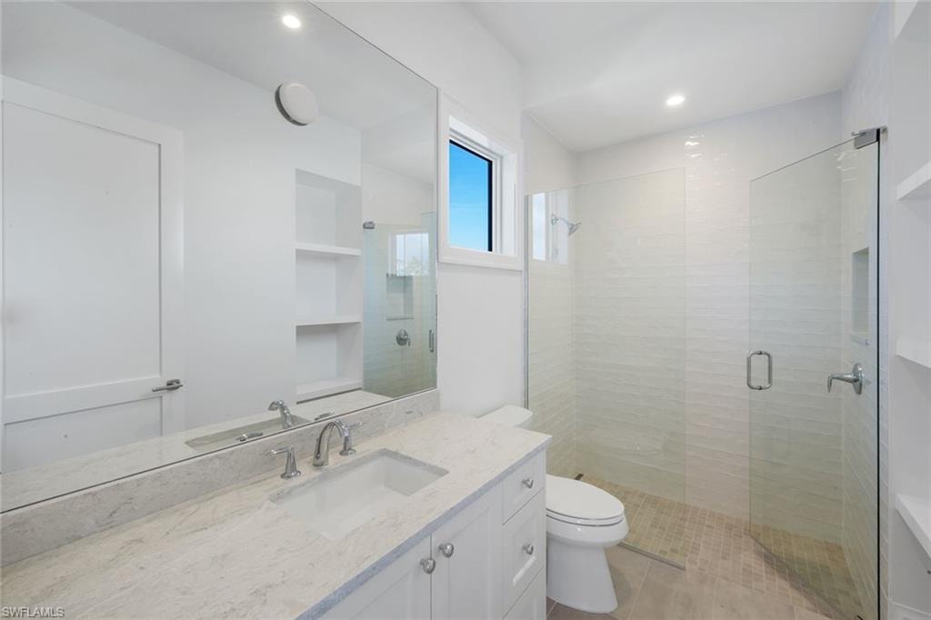 Bathroom with a shower stall, vanity, and recessed lighting