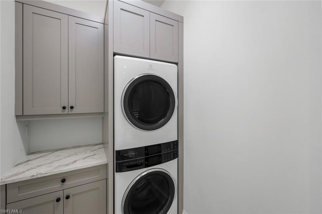 Laundry area with stacked washer and clothes dryer and cabinet space