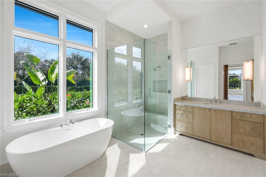 Full bath with a freestanding tub, a shower stall, vanity, and light tile patterned floors