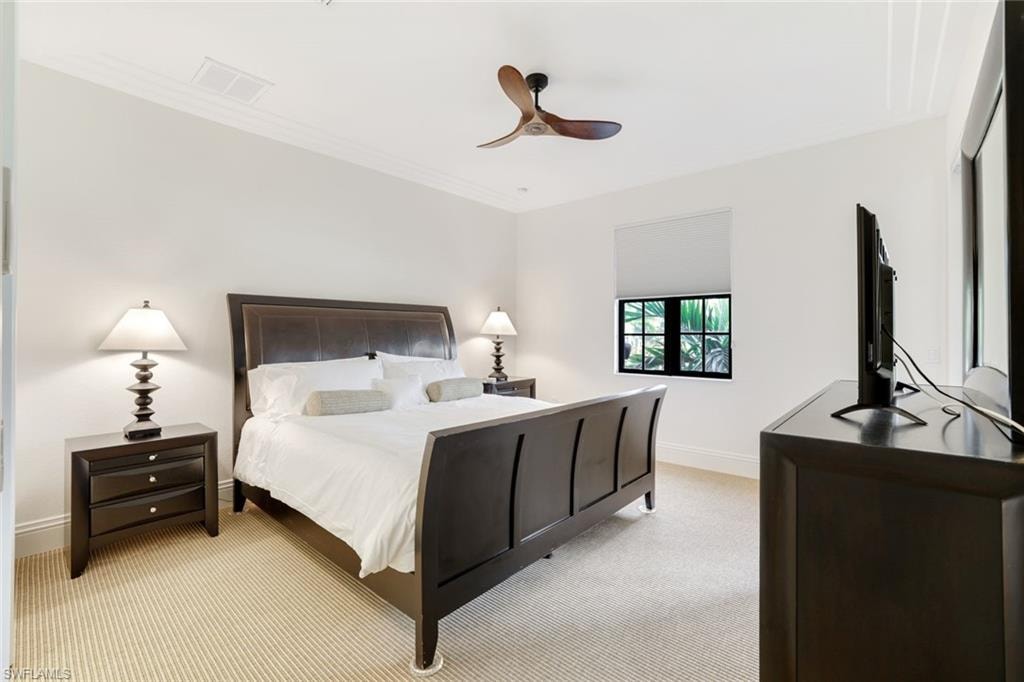 Bedroom with light colored carpet, a ceiling fan, and crown molding