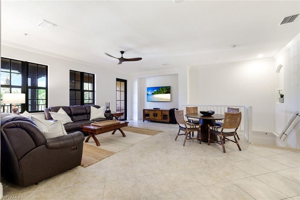 Living room with ceiling fan, ornamental molding, and light tile patterned floors