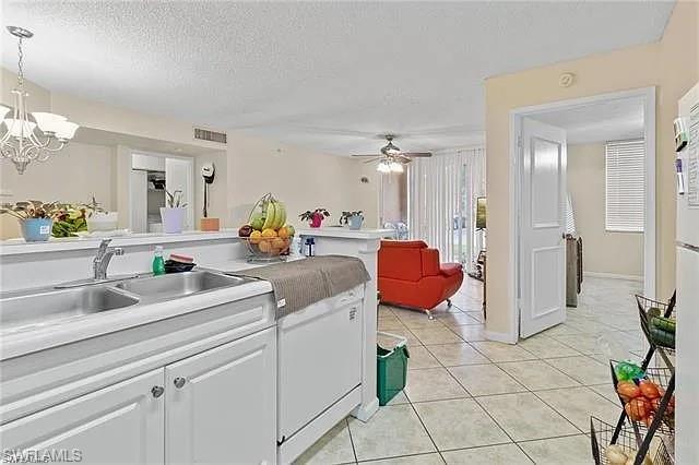 Kitchen featuring white cabinetry, light countertops, a textured ceiling, light tile patterned flooring, and a chandelier