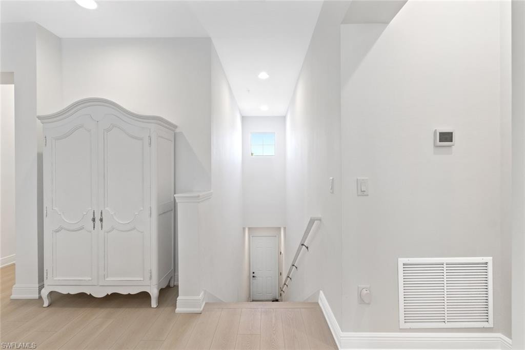 Hallway featuring an upstairs landing, light wood-style flooring, and recessed lighting