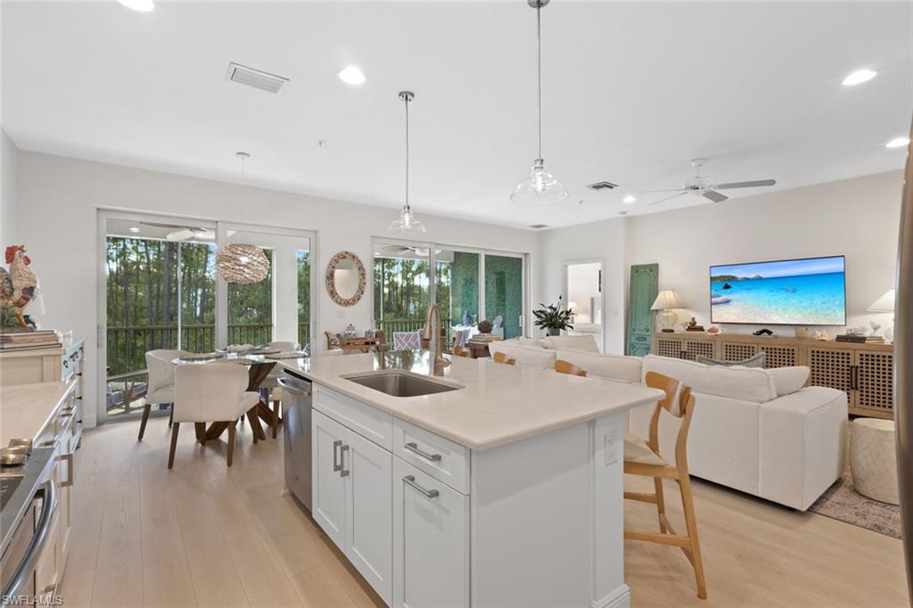 Kitchen with white cabinetry, open floor plan, light wood-type flooring, pendant lighting, and stainless steel appliances