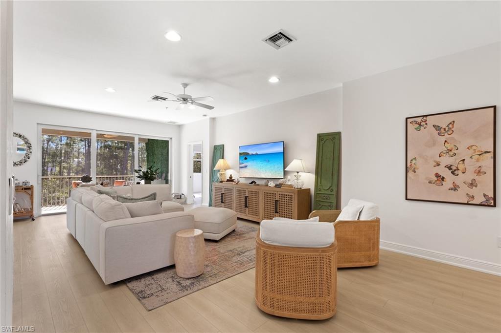 Living room featuring light wood-style flooring, ceiling fan, and recessed lighting