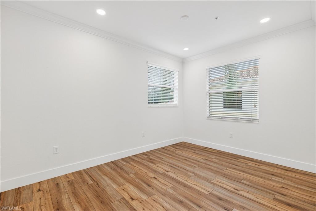 Empty room featuring light wood-type flooring, crown molding, and recessed lighting