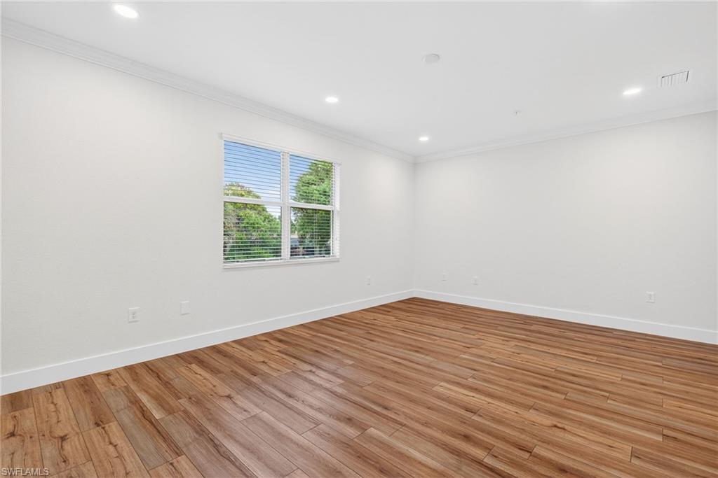 Spare room featuring light wood-style floors, crown molding, and recessed lighting