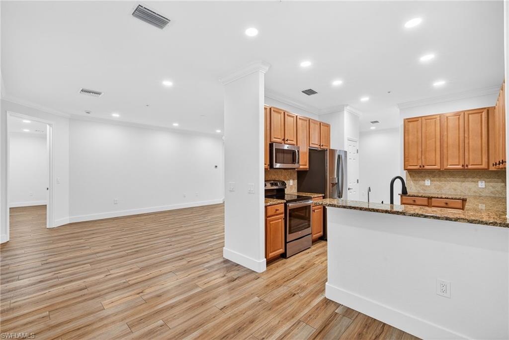 Kitchen featuring crown molding, stainless steel appliances, recessed lighting, dark stone countertops, and tasteful backsplash