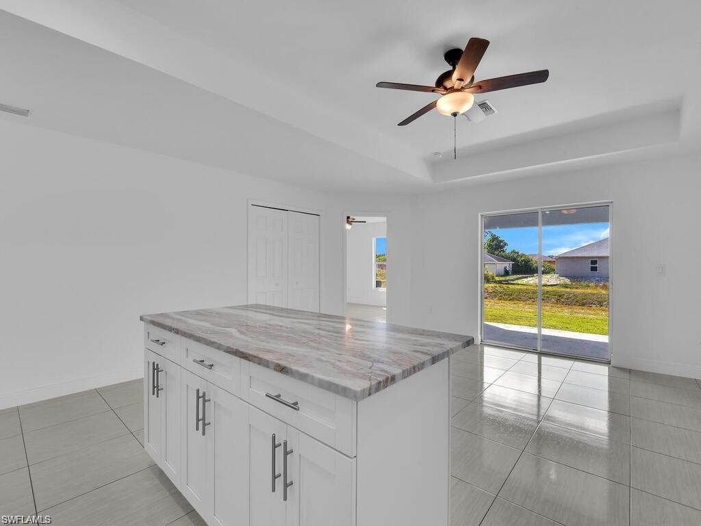 Kitchen with white cabinetry, a raised ceiling, and a ceiling fan over dinning area