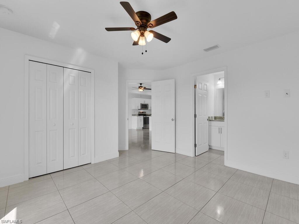 Primary Unfurnished bedroom with a ceiling fan, on suite and large closet