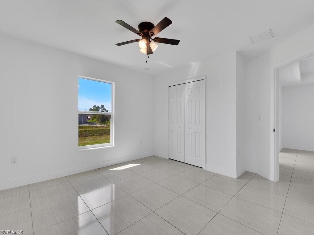 Unfurnished bedroom featuring a ceiling fan, a closet, and light tile patterned floors