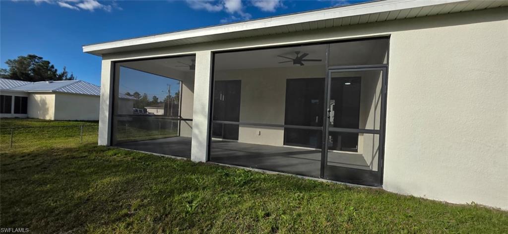 Doorway to property with a sunroom, stucco siding, and ceiling fan