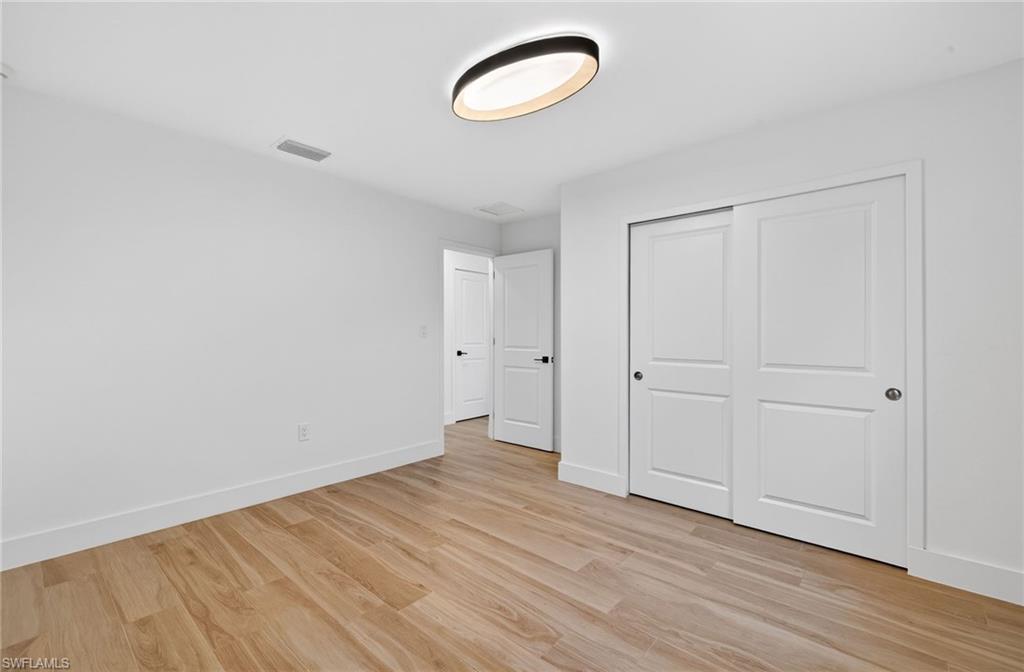 Unfurnished bedroom with light wood-style floors and a closet