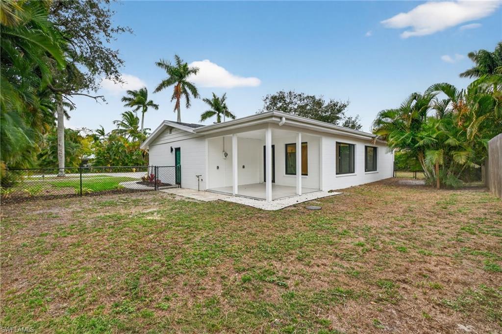 Rear view of house with a fenced backyard and a patio