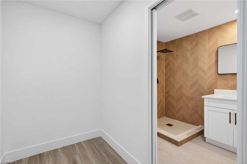 Bathroom with vanity, a shower stall, and light wood-type flooring